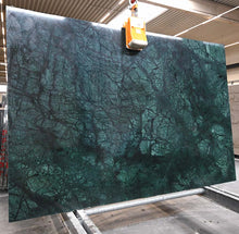 Lade das Bild in den Galerie-Viewer, Große grüne Verde-Guatemala-Natursteinplatte mit markanten dunklen Adern an einer Hebevorrichtung in einer Werkhalle